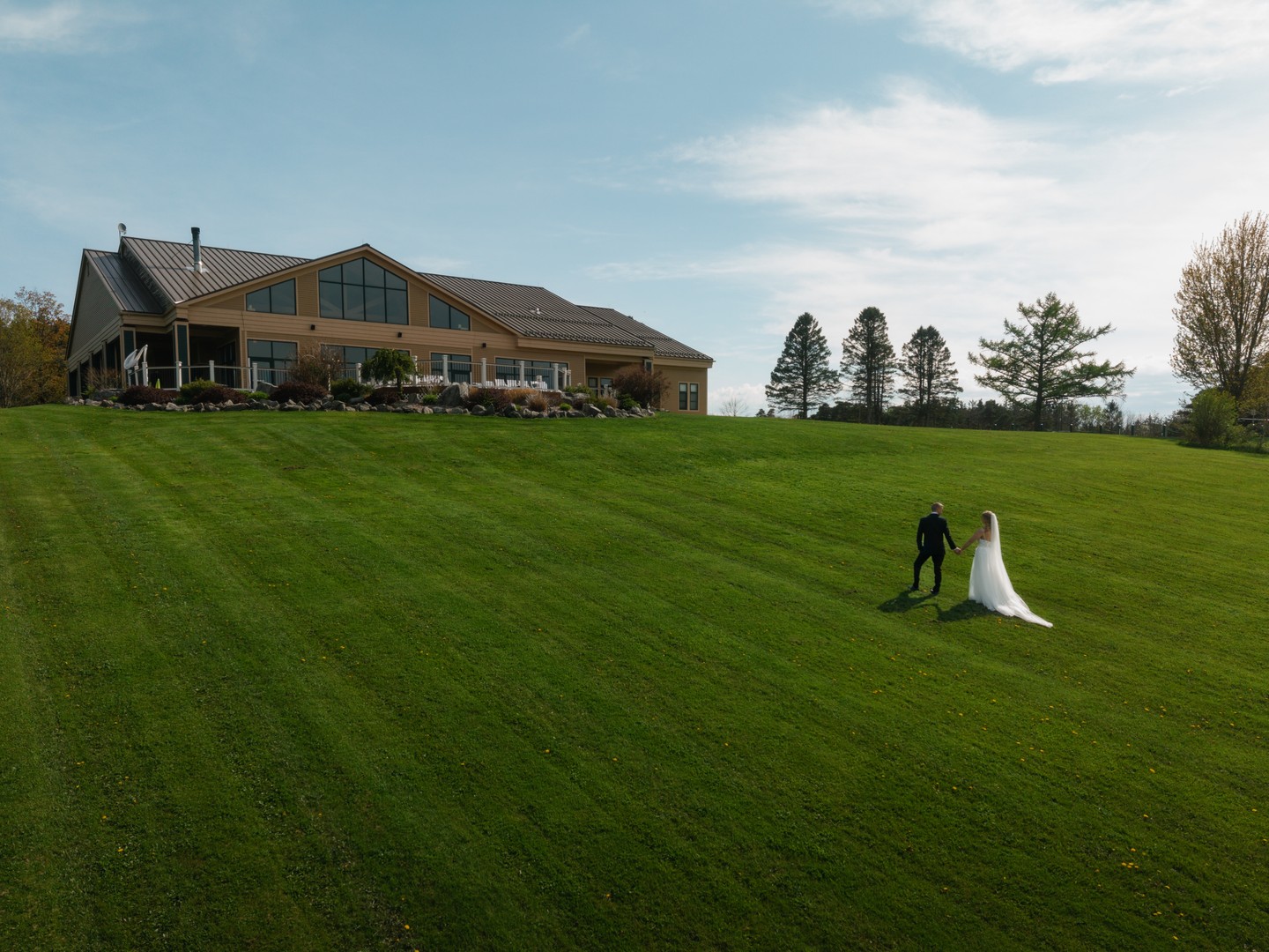 Skyline Lodge on its hilltop at Highland Forest in Fabius, New York, with Britney and Mike walking across the wide lawn below the lodge